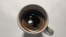 Slow motion water Drops in a Cup of black coffee