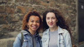Slowmotion stående för närbild av två lyckliga studenter afrikansk amerikan och Caucasian seende kamera och skratta blandat arkivfilmer Slowmotion stående för närbild av två lyckliga studenter afrikansk amerikan och Caucasian seende kamera och skratta blandat arkivfilmer