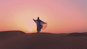 SLOWMOTION. Women wearing beautiful blue and white Arab clothes rising her hands at the desert