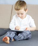 Sluit omhoog leuke slim weinig jongenszitting op laag bij de woonkamer en het gebruiken van touchscreen tablet Online Onderwijs v royalty-vrije stock foto's Sluit omhoog leuke slim weinig jongenszitting op laag bij de woonkamer en het gebruiken van touchscreen tablet Online Onderwijs v royalty-vrije stock foto's