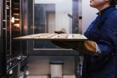 Sluit omhoog mening van de holdingsrek van de vrouwenholding van snoepjes in een bakkerij royalty-vrije stock foto's Sluit omhoog mening van de holdingsrek van de vrouwenholding van snoepjes in een bakkerij royalty-vrije stock foto's