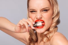 Sluit omhoog portret van aantrekkelijk meisje die haar lippen rouging Zij houdt rode lippenstift in de muis Geïsoleerd op grijs royalty-vrije stock afbeeldingen Sluit omhoog portret van aantrekkelijk meisje die haar lippen rouging Zij houdt rode lippenstift in de muis Geïsoleerd op grijs royalty-vrije stock afbeeldingen