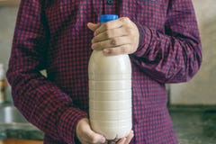 Sluit omhoog toevallige persoon die een fles melk in huiskeuken houden stock afbeelding Sluit omhoog toevallige persoon die een fles melk in huiskeuken houden stock afbeelding