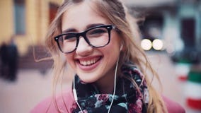 Sluit omhoog van een jong leuk meisje die met hoofdtelefoons charmingly net naar de camera, toevallig kapsel glimlachen Mooi stock video Sluit omhoog van een jong leuk meisje die met hoofdtelefoons charmingly net naar de camera, toevallig kapsel glimlachen Mooi stock video