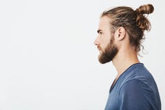 Sluit omhoog van knappe gebaarde hipsterkerel met haar in broodje, in blauwe t-shirt die zich in profiel bevinden, opzij kijkend royalty-vrije stock foto Sluit omhoog van knappe gebaarde hipsterkerel met haar in broodje, in blauwe t-shirt die zich in profiel bevinden, opzij kijkend royalty-vrije stock foto