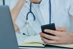 Slut upp den manliga doktorn eller medicinaren som använder den smarta telefonen för mobil som arbetar på bärbar datordatoren i s arkivfoton Slut upp den manliga doktorn eller medicinaren som använder den smarta telefonen för mobil som arbetar på bärbar datordatoren i s arkivfoton