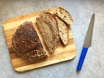 Släntrar artisanal bröd för Sourdough och skivor på träskärbräda arkivbild Släntrar artisanal bröd för Sourdough och skivor på träskärbräda arkivbild