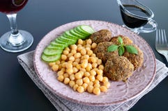 Smakliga köttkotletter, kikärtar, ny gurka på en keramisk platta och ett exponeringsglas av vin fotografering för bildbyråer Smakliga köttkotletter, kikärtar, ny gurka på en keramisk platta och ett exponeringsglas av vin fotografering för bildbyråer