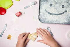 Small baby hands mold the heart from a homemade dough. Smiley on a tray of flour royalty free stock photography Small baby hands mold the heart from a homemade dough. Smiley on a tray of flour royalty free stock photography