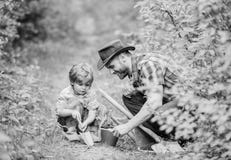 Small boy child help father in farming. Eco farm. father and son in cowboy hat on ranch. hoe, pot and shovel. Garden royalty free stock photography Small boy child help father in farming. Eco farm. father and son in cowboy hat on ranch. hoe, pot and shovel. Garden royalty free stock photography