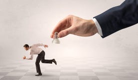 Small businessman running away from big hand with chessman concept royalty free stock photos Small businessman running away from big hand with chessman concept royalty free stock photos