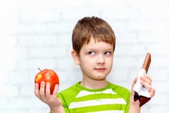 Small Child Chooses Chocolate Or Apple Stock Photos
