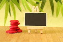 Small empty slate in width to write a message that is posed on an easel with zen lifestyle red stones all on wooden floor and gre Stock Photos Small empty slate in width to write a message that is posed on an easel with zen lifestyle red stones all on wooden floor and gre Stock Photos