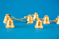 Small gold bell decorations on blue background. Holidays concept.