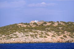 Small greek island on Mediterranean Sea, rocky islet with scant vegetation and traditional church chapel. stock photo Small greek island on Mediterranean Sea, rocky islet with scant vegetation and traditional church chapel. stock photo