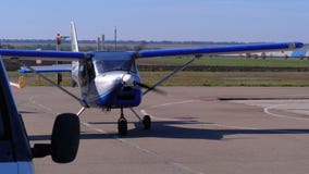 Small private airplane with a rotating propeller standing on the aircraft parking on a small airfield
