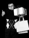 Small smiling boy or cute nerd kid in glasses, hat and fashionable knitted scarf on black background holds white present royalty free stock image Small smiling boy or cute nerd kid in glasses, hat and fashionable knitted scarf on black background holds white present royalty free stock image