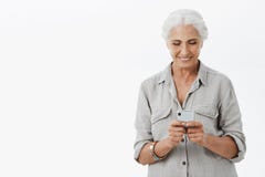 Smart and creative granny uses smartphone easily. Portrait of charming pleased senior woman with grey hair holding royalty free stock photo Smart and creative granny uses smartphone easily. Portrait of charming pleased senior woman with grey hair holding royalty free stock photo