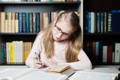 Smart little girl with glasses writing on book, stock image Smart little girl with glasses writing on book, stock image