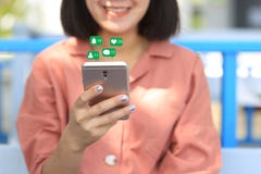 Smartphone da terra arrendada da mão da mulher para verificar meios sociais com o ícone ou o holograma na cafetaria, Internet da fotografia de stock Smartphone da terra arrendada da mão da mulher para verificar meios sociais com o ícone ou o holograma na cafetaria, Internet da fotografia de stock