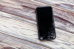 Smartphone do preto do loseup do ¡ de Ð com o vidro quebrado da tela que encontra-se na tabela de madeira Conceito do telefone de fotos de stock Smartphone do preto do loseup do ¡ de Ð com o vidro quebrado da tela que encontra-se na tabela de madeira Conceito do telefone de fotos de stock