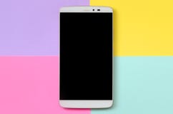 Smartphone moderno con la pantalla negra en el fondo de la textura del papel azul de la moda, amarillo, violeta y rosado en color imagen de archivo libre de regalías Smartphone moderno con la pantalla negra en el fondo de la textura del papel azul de la moda, amarillo, violeta y rosado en color imagen de archivo libre de regalías
