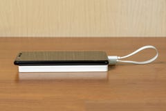 Smartphone preto que carrega com o banco branco do poder através do cabo de USB, vista lateral imagens de stock Smartphone preto que carrega com o banco branco do poder através do cabo de USB, vista lateral imagens de stock