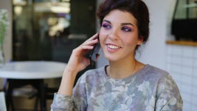Smartphone woman talking on phone while sitting in cafe. She is smiling. Beautiful young female having casual stock video Smartphone woman talking on phone while sitting in cafe. She is smiling. Beautiful young female having casual stock video