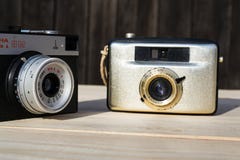 Smena 8M and Penti I old vintage golden cameras on wooden background stock photos Smena 8M and Penti I old vintage golden cameras on wooden background stock photos