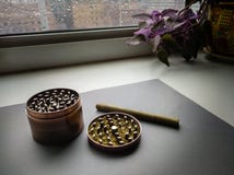 Smerigliatrice dell'erba con marijuana ed il Cigarillo a terra fotografia stock Smerigliatrice dell'erba con marijuana ed il Cigarillo a terra fotografia stock