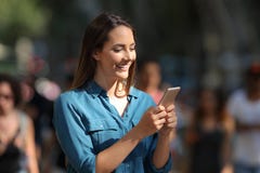 Smiley girl using a smart phone walking in the street Royalty Free Stock Photo Smiley girl using a smart phone walking in the street Royalty Free Stock Photo