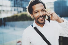 Smiling American African man using smartphone to call friends at sunny street.Concept of happy young handsome people stock images Smiling American African man using smartphone to call friends at sunny street.Concept of happy young handsome people stock images