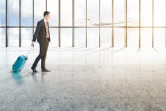 Smiling asian businessman with blue suitcase walking on the airport hall stock photo Smiling asian businessman with blue suitcase walking on the airport hall stock photo