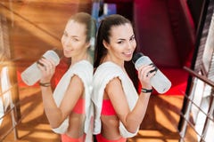 Smiling attractive woman athlete drinking water in gym stock image Smiling attractive woman athlete drinking water in gym stock image