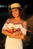 Beautiful woman with curly brown hair holding apples in her hands in the garden