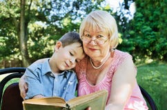 Smiling boy and his grandmother reading a book in the park stock photography Smiling boy and his grandmother reading a book in the park stock photography
