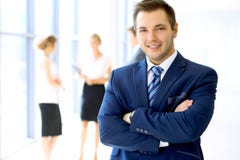 Smiling businessman in office with colleagues in the background stock photography Smiling businessman in office with colleagues in the background stock photography