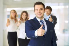 Smiling businessman in office with colleagues in the background. Thumbs up! stock photography Smiling businessman in office with colleagues in the background. Thumbs up! stock photography
