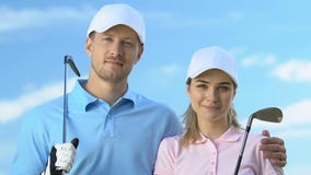 Smiling couple of golfers posing with clubs against blue sky, golf club trainers stock video Smiling couple of golfers posing with clubs against blue sky, golf club trainers stock video