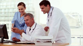 Smiling doctor showing something to his colleagues on his computer
