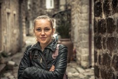 Smiling frozen beautiful woman standing on narrow medieval street during her travel holidays around Europe in cold overcast rainy stock image Smiling frozen beautiful woman standing on narrow medieval street during her travel holidays around Europe in cold overcast rainy stock image