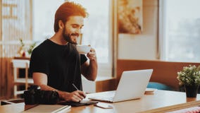 Smiling Guy Drinks Tea While Working on Laptop stock photography Smiling Guy Drinks Tea While Working on Laptop stock photography