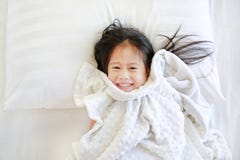 Smiling Little Asian Child Girl Lying On Bed With Blanket And Looking At Camera. Above View Royalty Free Stock Photos Smiling Little Asian Child Girl Lying On Bed With Blanket And Looking At Camera. Above View Royalty Free Stock Photos