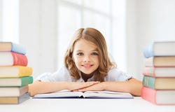 Smiling little student girl with many books