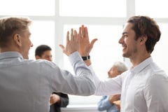 Smiling male colleagues giving high five in office celebrating v stock images Smiling male colleagues giving high five in office celebrating v stock images