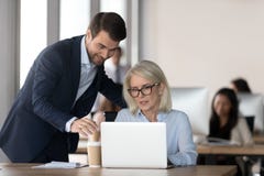 Smiling millennial manager help mature woman with laptop royalty free stock images Smiling millennial manager help mature woman with laptop royalty free stock images