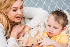 Smiling mother watching son playing with wooden airplane stock image Smiling mother watching son playing with wooden airplane stock image