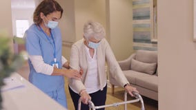 Nurse helping senior woman walk at nursing home