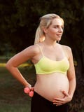 Smiling pregnant woman caress her belly at nature stock photos Smiling pregnant woman caress her belly at nature stock photos