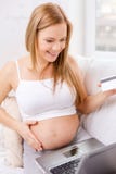 Smiling pregnant woman with laptop computer